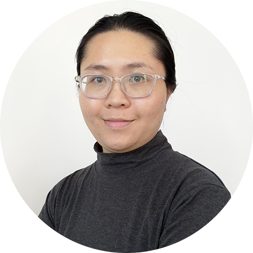 A person with glasses and dark hair pulled back is wearing a dark turtleneck and smiling slightly against a plain white background.