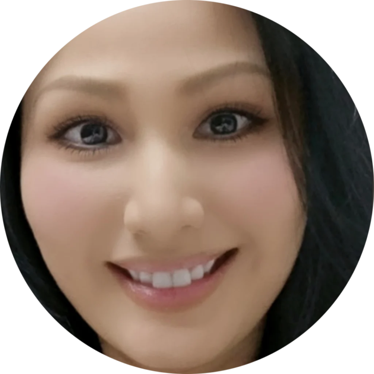 A person with long dark hair is smiling at the camera. The image is a close-up showing their face and eyes clearly.