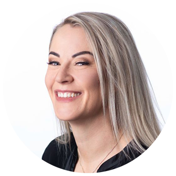 Portrait of a person with long blonde hair, smiling, wearing a black top against a white background.